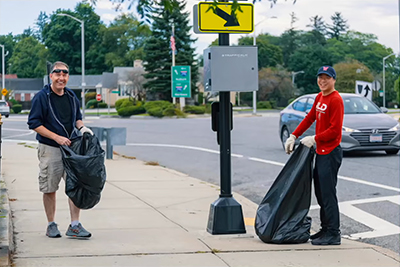 Two Quality of Life Team Members with Trash Bag Picking Up Trash on Sidewalk